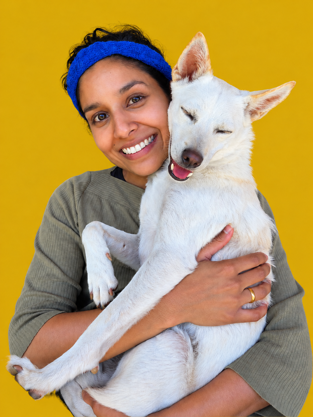 Sapana smiling while holding her white dog Neo against a golden background