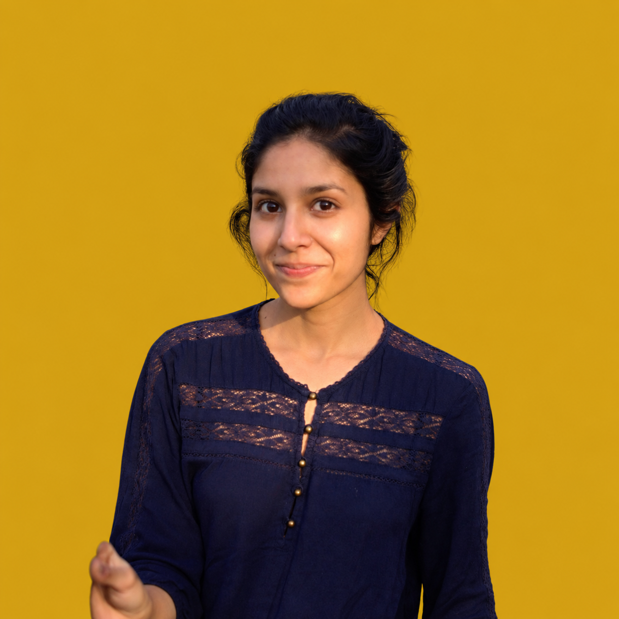 Sapana smiling against a golden yellow background